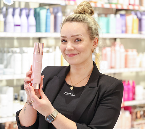 Medarbejder viser skønhedsprodukt frem i butikken